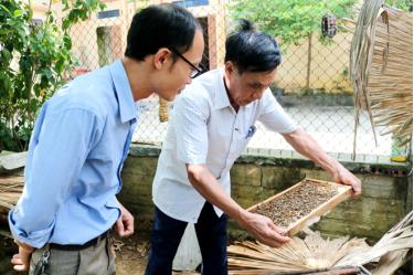 Cán bộ Phòng Lao động - Thương binh và Xã hội huyện Yên Bình thăm mô hình nuôi ong của gia đình thương binh Nguyễn Thu Hưởng.