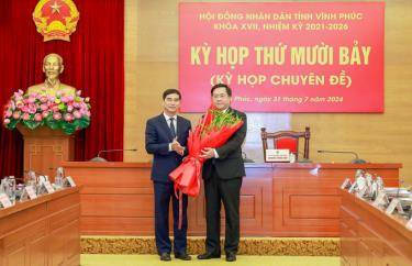 Tân Chủ tịch UBND tỉnh Vĩnh Phúc Trần Duy Đông (phải) nhận hoa chúc mừng từ Bí thư Tỉnh ủy Vĩnh Phúc Dương Văn An. Ảnh: Báo Vĩnh Phúc
