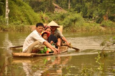 Người dân và các em học sinh thôn 11 hàng ngày phải di chuyển qua vùng gập bằng thuyền gỗ rất nguy hiểm.