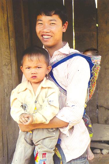 Tảo hôn, đẻ dày, đẻ nhiều đang là vấn nạn ở vùng cao gây khó khăn trong xây dựng gia đình bền vững.
Trong ảnh: Một thanh niên ở bản Lìm Thái, xã Cao Phạ tay bế đứa con 2 tuổi và địu đứa con 1 tuổi sau lưng.
