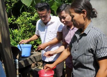 Cán bộ y tế thành phố hướng dẫn người dân xã Tuy Lộc xử lý nước sinh hoạt sau mưa lũ.
