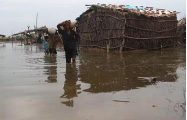 Người dân lội qua khu vực ngập lụt sau trận mưa lớn ở Sanghar, Pakistan.