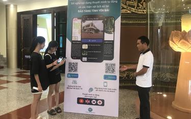 Cán bộ Bảo tàng tỉnh Yên Bái hướng dẫn khách tham quan tải và sử dụng ứng dụng thuyết minh tự động.