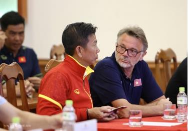 HLV Hoàng Anh Tuấn (áo đỏ) trao đổi cùng HLV Troussier trong lễ mừng công của đội U23 Việt Nam ở trụ sở VFF chiều 27/8.