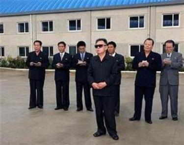Chủ tịch Kim (đứng giữa) trong chuyến thăm đến một nhà máy của Triều Tiên.