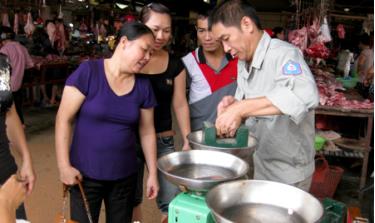 Kiểm định phương tiện đo là cân thông dụng dùng trong kinh doanh tại chợ Yên Bình. (Ảnh Thanh Sơn)