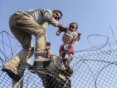 Người di cư Syria cố vượt qua hàng rào dây thép gai để vào lãnh thổ Thổ Nhĩ Kỳ.
