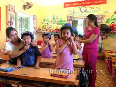 Giáo viên Trường Tiểu học Lý Tự Trọng hướng dẫn học sinh đội mũ bảo hiểm đúng quy cách.