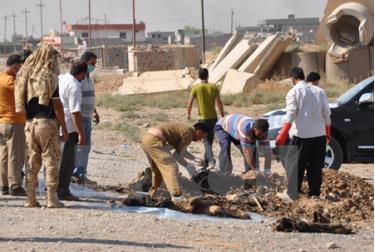 Người dân Iraq đưa xác các nạn nhân lên khỏi một hố chôn tập thể.