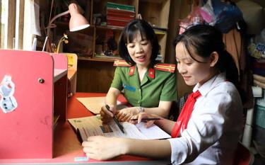 Trung tá Đinh Thị Thu Hương - Đội trưởng Đội Cảnh sát quản lý hành chính về trật tự xã hội, Công an huyện Trấn Yên giúp đỡ em Phạm Thị Kiều Vân trong học tập.