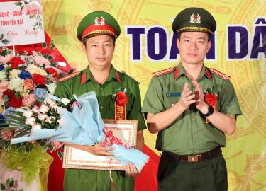 Thiếu tá Bùi Hồng Huấn (trái) nhận Bằng khen của Bộ Công an.