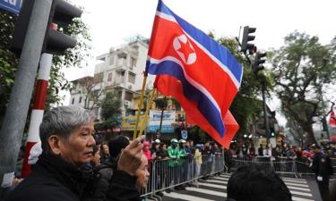 Người dân cầm cờ Việt Nam và Triều Tiên đứng chờ đoàn xe của Chủ tịch Kim Jong-un gần khách sạn Melia ở Hà Nội.