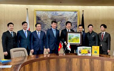 Chairman of the provincial People's Committee Tran Huy Tuan presents a photo of Mu Cang Chai terraced field to Mayor of Maebashi city Yamamoto Ryu.