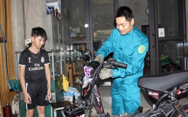 Tổ đội trưởng Nguyễn Mạnh Linh đang sửa chữa xe đạp điện tại cửa hàng sửa xe máy của gia đình.
