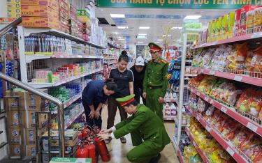 Cán bộ Đội Cảnh sát Quản lý hành chính về trật tự xã hội, Công an Lục Yên hướng dẫn tiểu thương sử dụng công cụ chữa cháy.