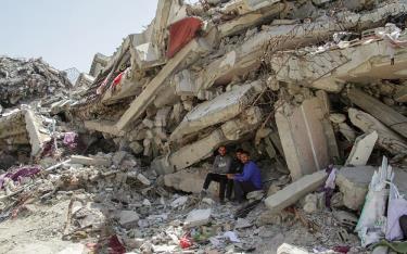 Người Palestine ngồi bên đống đổ nát sau một cuộc tấn công của Israel tại phía bắc Gaza hôm 22/4.