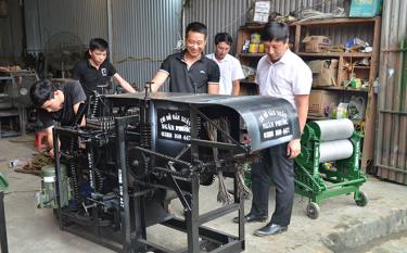 Anh Vũ Văn Ngân (đững giữa) đang giới thiệu chiếc máy bóc vỏ cành quế với lãnh đạo xã Yên Phú. 
