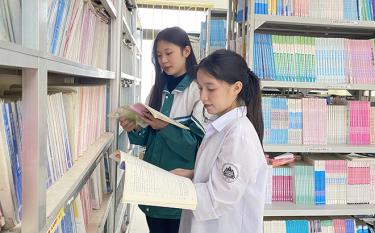 Em Trần Thị Đào và em Bàn Kim Thư chăm chỉ tìm đọc tài liệu trong thư viện nhà trường.