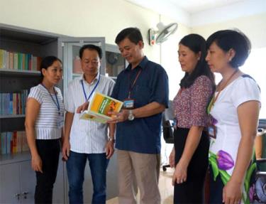 Đồng chí Nguyễn Huy Cường - Giám đốc Sở Tư pháp (người đứng giữa) trao đổi với cán bộ Phòng Phổ biến, giáo dục pháp luật  về công tác xây dựng tủ sách pháp luật ở cơ sở.