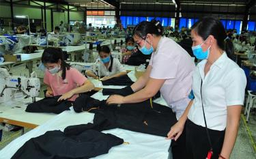 Employees of Unico Global YB Co. Ltd check the quality of garment products.