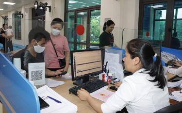 Cán bộ Bộ phận Phục vụ hành chính công thành phố Yên Bái hướng dẫn người dân nộp hồ sơ trực tuyến.