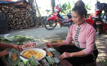 Cô gái Thái Mường Lò gói bánh chưng đen - một trong những loại bánh truyền thống được đông đảo du khách ưa thích.
